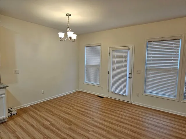 an empty room with wooden floor chandelier and windows
