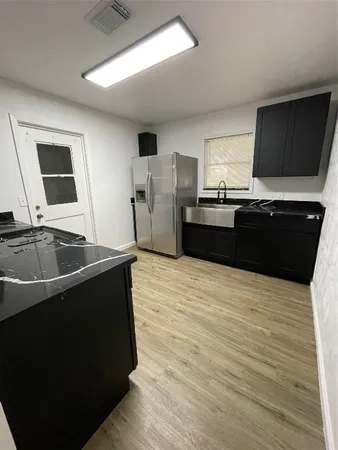 a kitchen with stainless steel appliances wooden cabinets granite counter tops and a black wooden floor