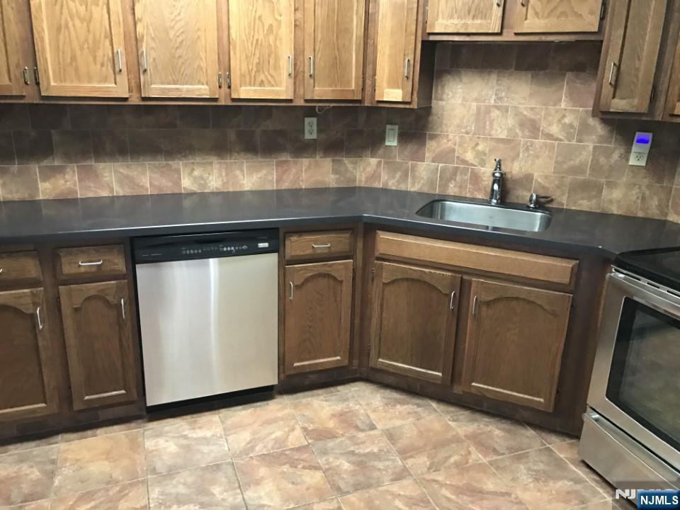 1040 Harmon Cove Tower, Unit 1040 Secaucus, NJ 07094 - Photo 5 of 15 a kitchen with granite countertop a sink a stove and cabinets