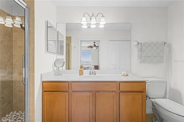 a bathroom with a sink a toilet a mirror and shower