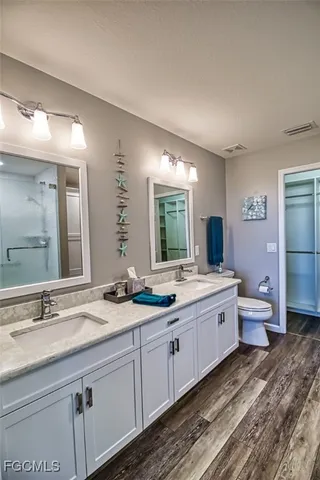 a bathroom with a granite countertop double vanity sink a mirror and a bathtub