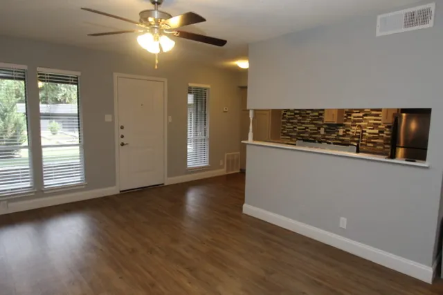 a view of a livingroom with wooden floor and a ceiling fan