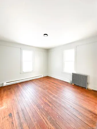 an empty room with wooden floor and fan