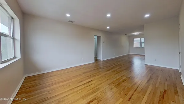 a view of empty room with wooden floor and fan