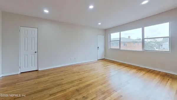 an empty room with wooden floor and windows