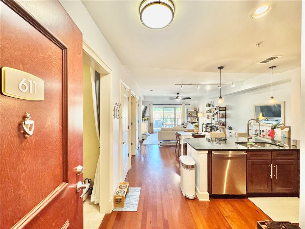 a dining hall with stainless steel appliances granite countertop a sink dishwasher and a stove with wooden floor
