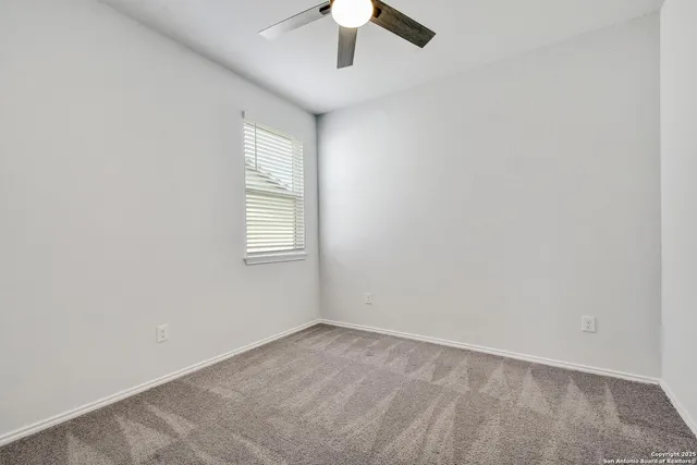 an empty room with a window and a ceiling fan