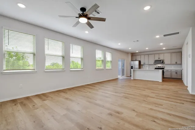 a view of an empty room with a window and a kitchen