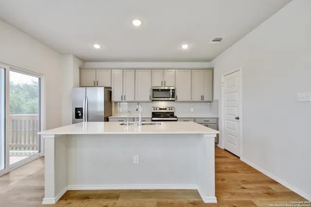 a view of a kitchen with stainless steel appliances granite countertop a refrigerator a stove top oven a sink and dishwasher