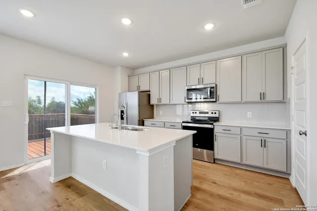 a kitchen with stainless steel appliances granite countertop a stove a sink a refrigerator white cabinets and a refrigerator