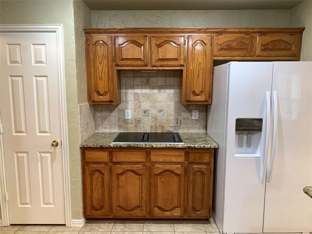 4914 Shadowood Road Colleyville, TX 76034 - Photo 19 of 28 Kitchen with white fridge with ice dispenser, brown cabinets, black electric stovetop, tasteful backsplash, and a textured wall
