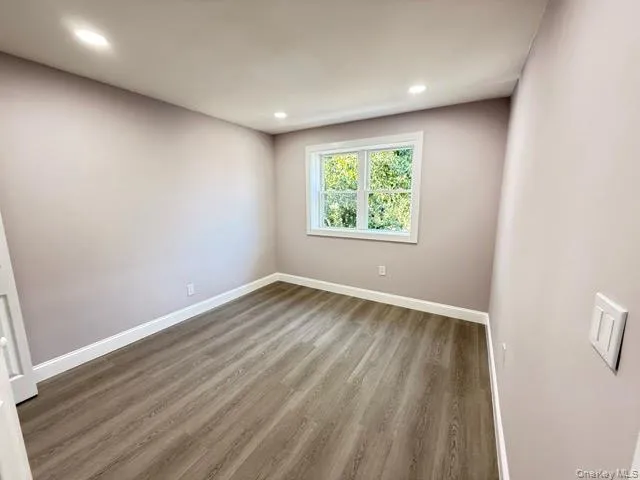 an empty room with wooden floor and window
