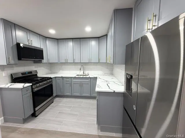 a large kitchen with stainless steel appliances granite countertop a refrigerator a sink a stove a microwave and wooden cabinets