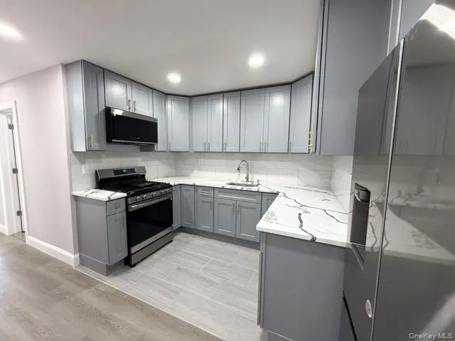 a kitchen with granite countertop a sink a counter top space stainless steel appliances and cabinets