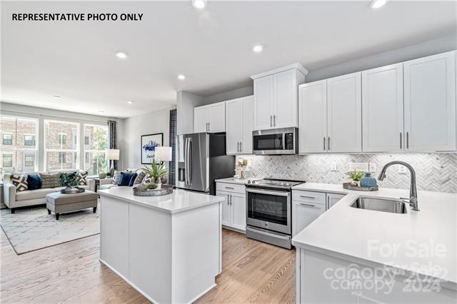 a large kitchen with stainless steel appliances granite countertop a stove refrigerator and a couch