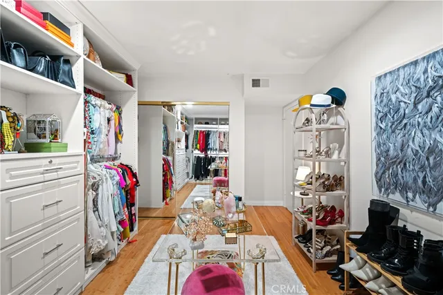 a view of walk in closet with clothes shoes and a large mirror