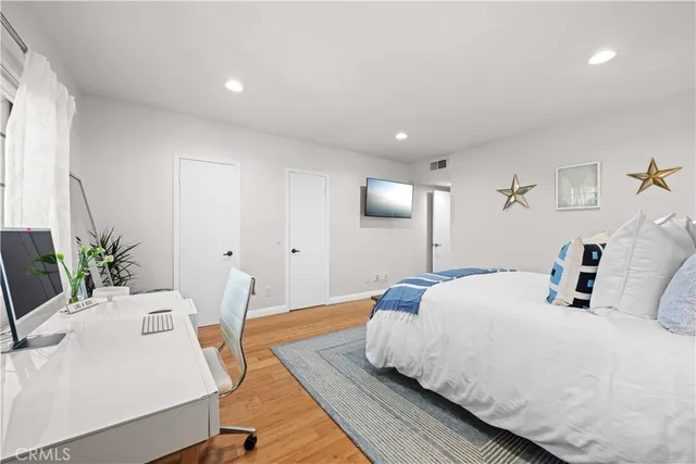 a spacious bedroom with a bed and wooden floor