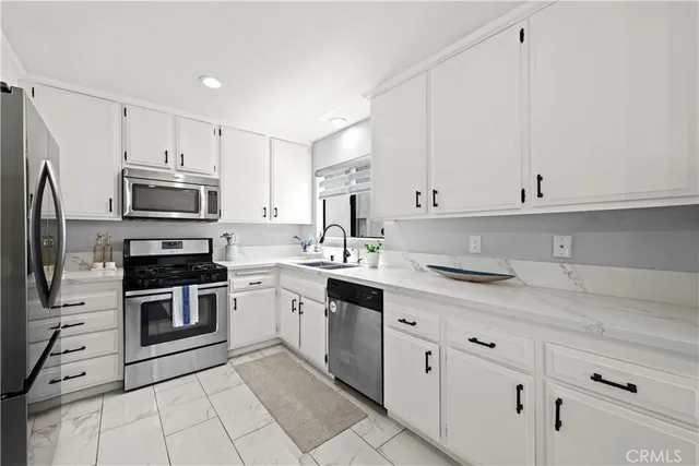a kitchen with granite countertop white cabinets and stainless steel appliances