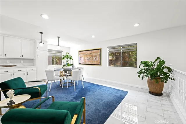 a living room with furniture potted plant and kitchen view