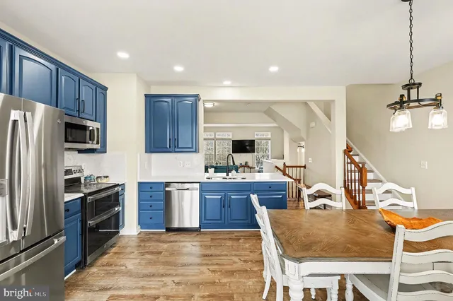 a kitchen with stainless steel appliances granite countertop a sink a stove a refrigerator cabinets a dining table and chairs