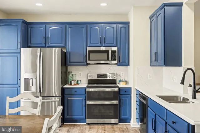 a kitchen with stainless steel appliances granite countertop a stove top oven a refrigerator and a sink with wooden cabinets