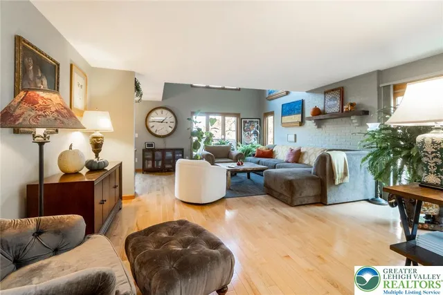 a living room with furniture a clock on the wall and a large window