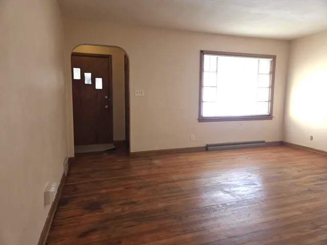 an empty room with wooden floor and window