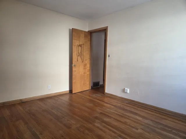 a view of an empty room with wooden floor and closet