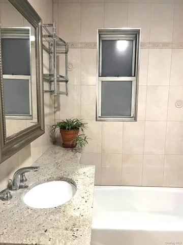 a bathroom with a granite countertop sink a mirror and a shower