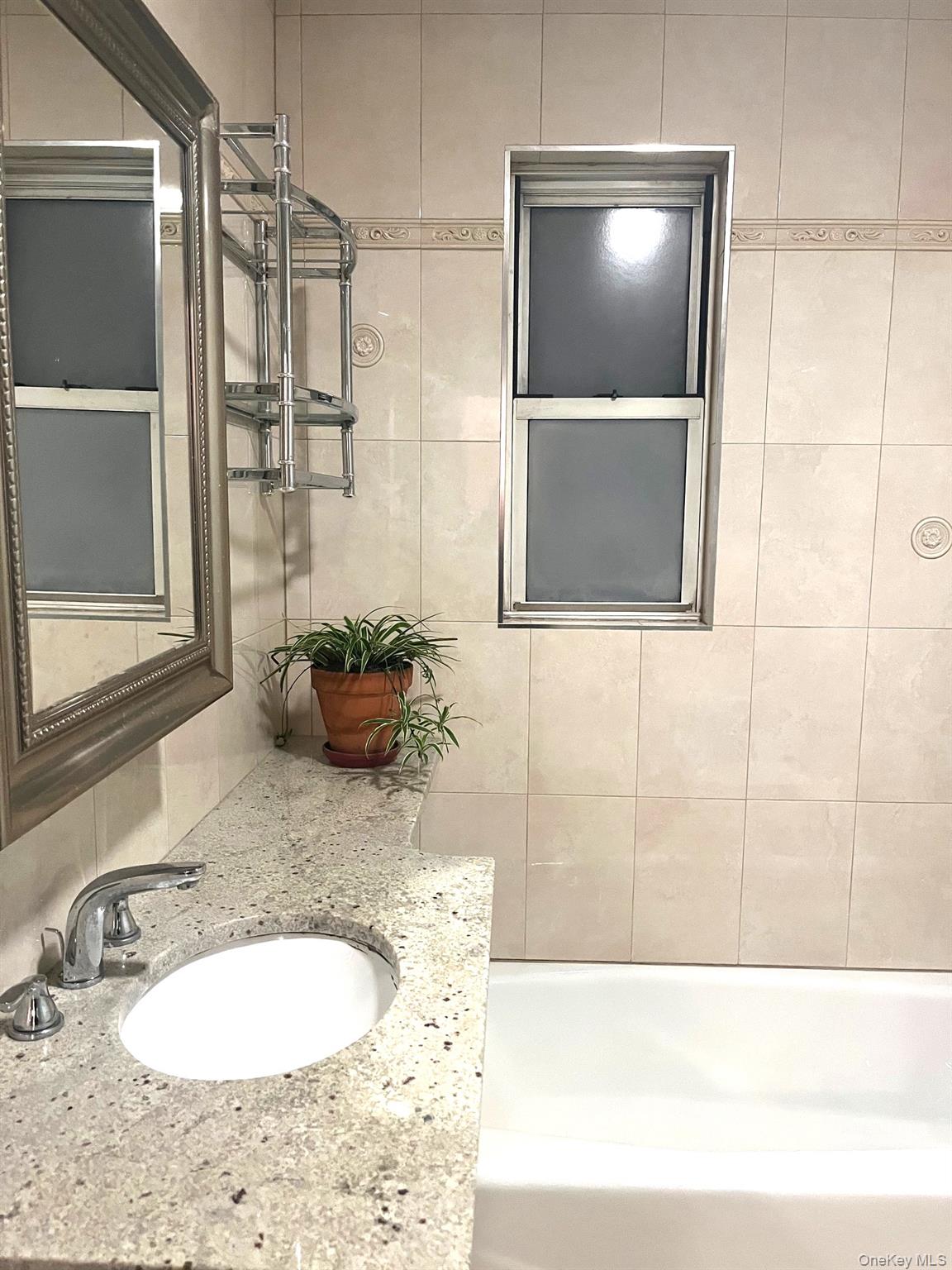 1945 Paulding Avenue Bronx, NY 10462 - Photo 6 of 12 a bathroom with a granite countertop sink a mirror and a shower