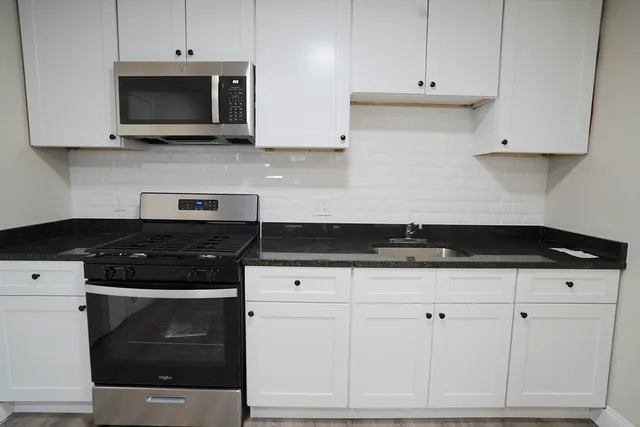 a kitchen with stainless steel appliances granite countertop white cabinets and a stove a oven with white countertops