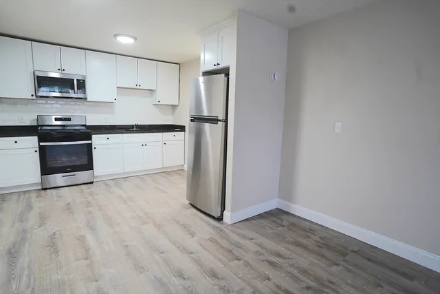 a kitchen with granite countertop a refrigerator and a stove top oven