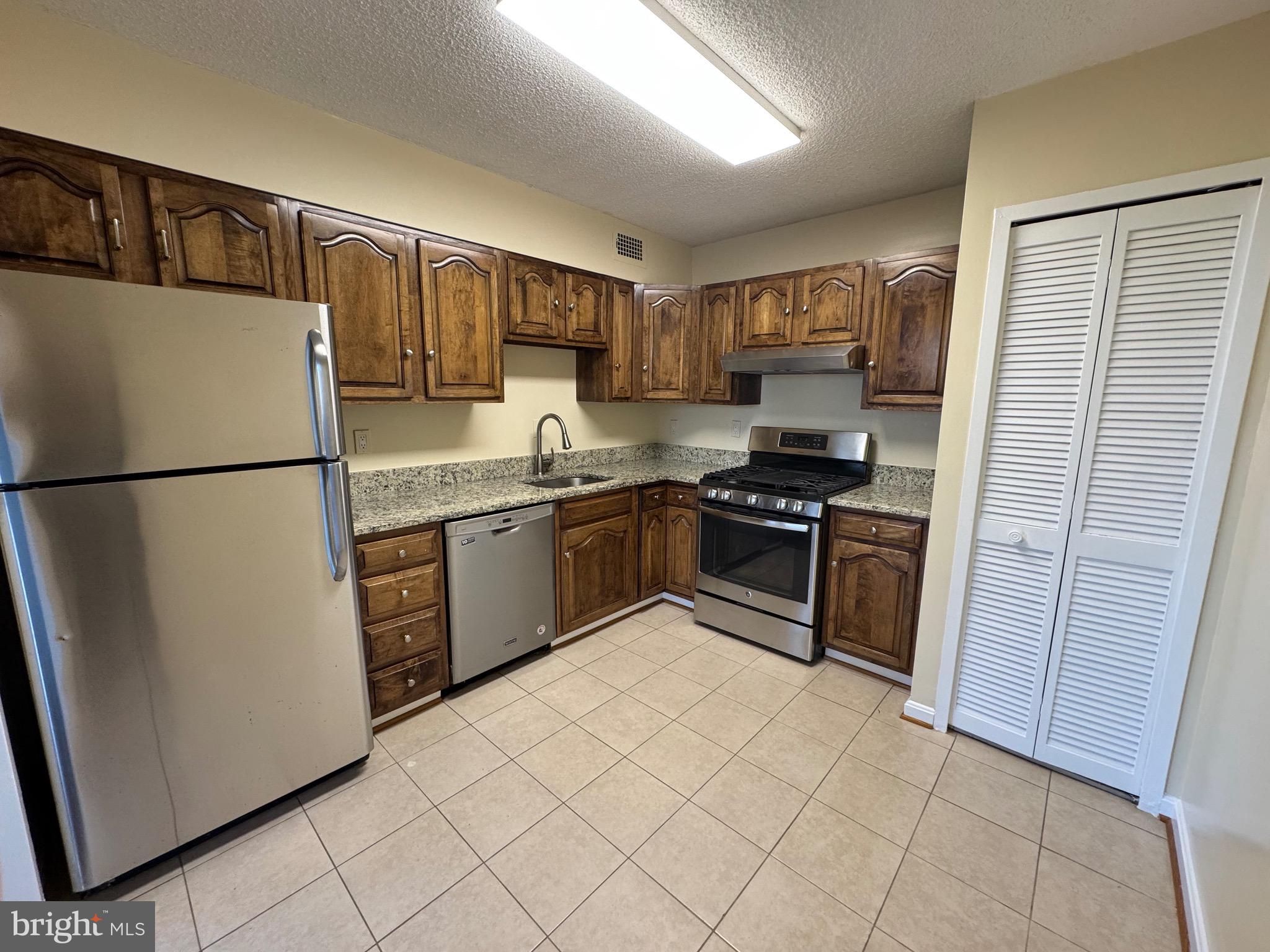 5225 Pooks Hill, Unit 710N Bethesda, MD 20814 - Photo 55 of 64 a kitchen with granite countertop a refrigerator and a stove top oven