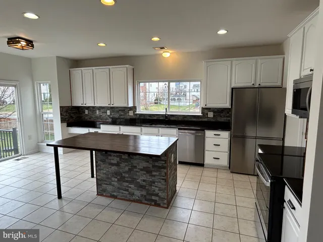 a kitchen with stainless steel appliances granite countertop a refrigerator a stove a sink and a microwave