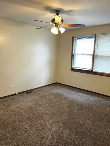 an empty room with a chandelier fan and windows
