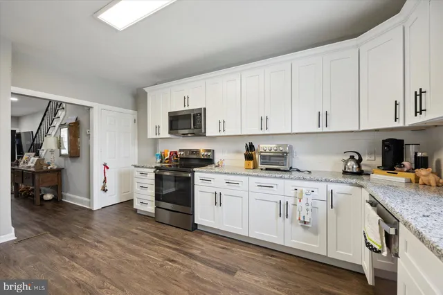 a kitchen with granite countertop white cabinets and stainless steel appliances