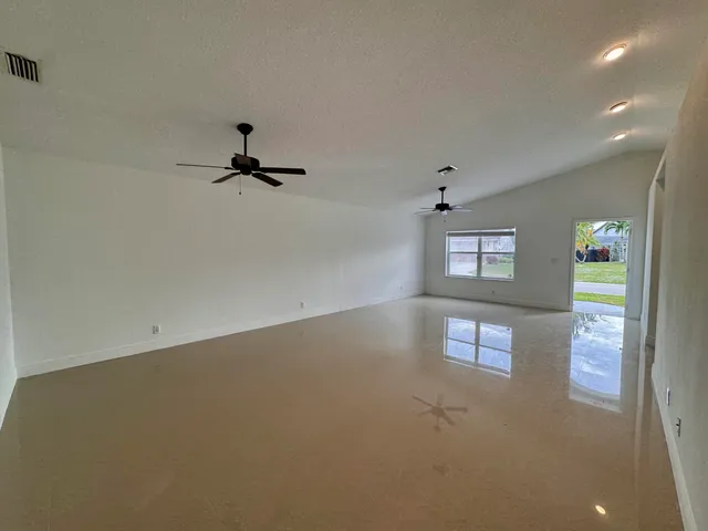 an empty room with windows and ceiling fan