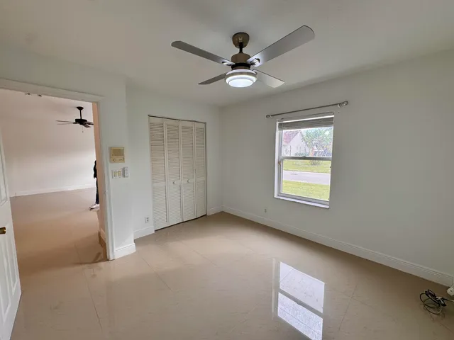 an empty room with closet and a ceiling fan