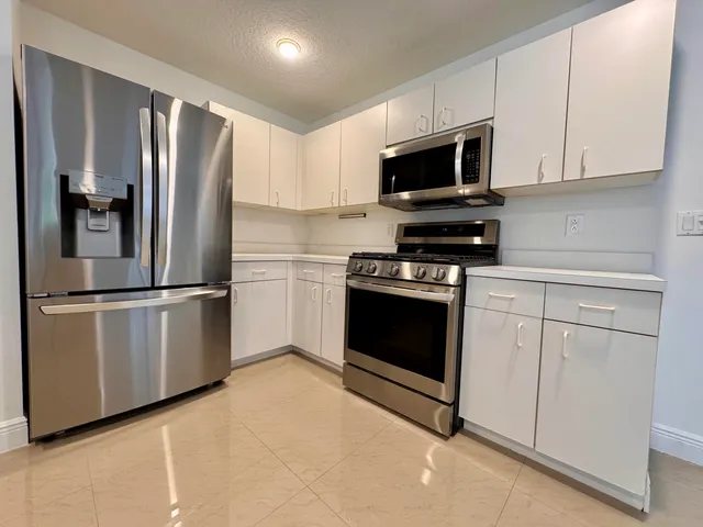 a kitchen with cabinets stainless steel appliances and wooden floor
