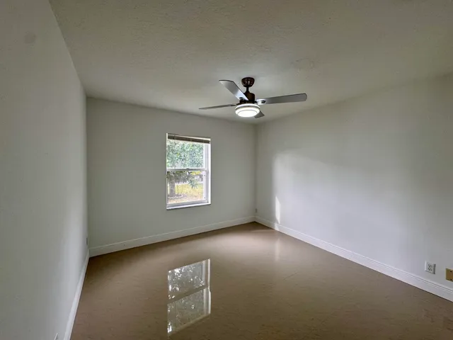 an empty room with a ceiling fan and a window