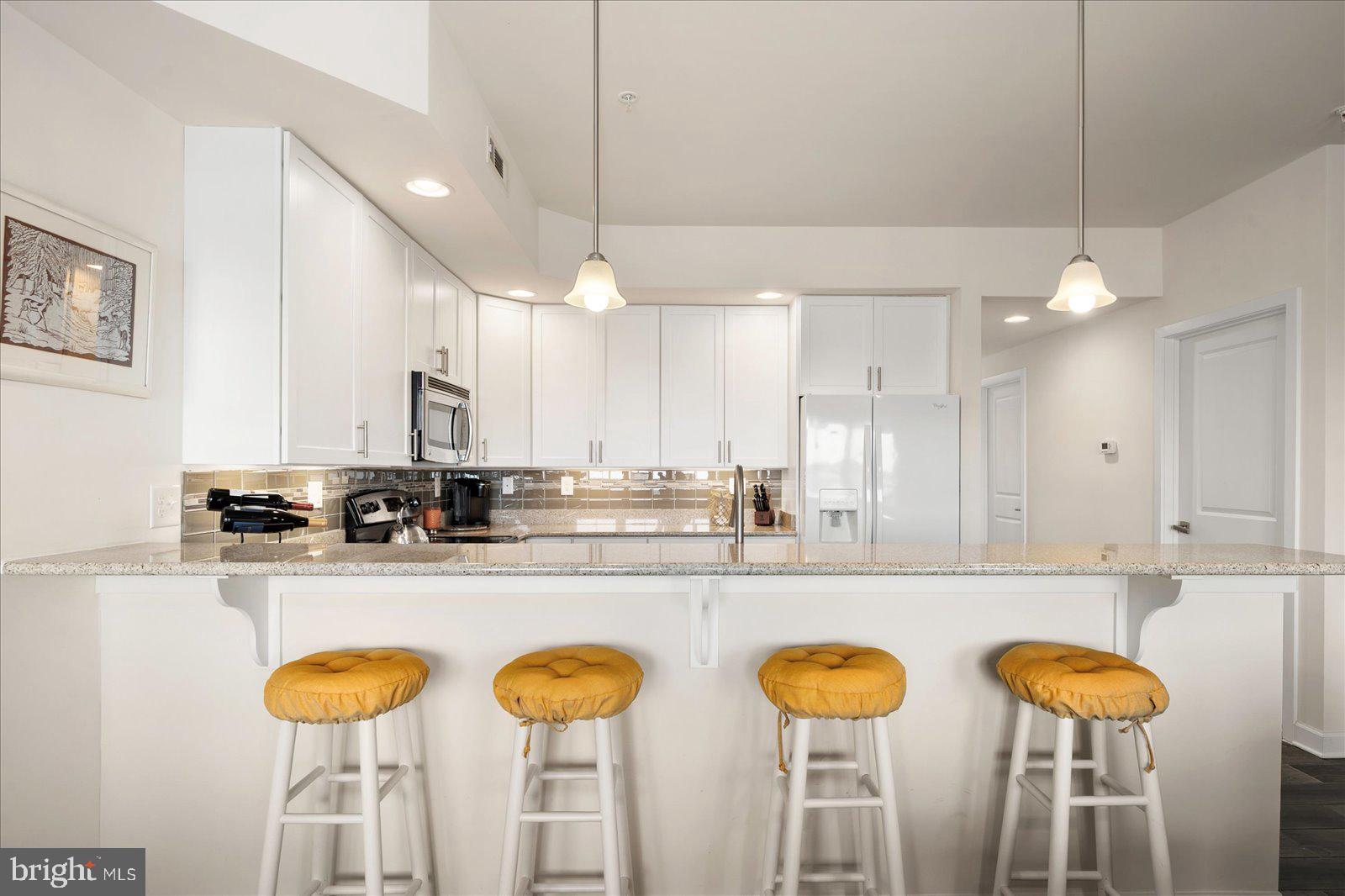 37292 Lighthouse Road, Unit 202 Selbyville, DE 19975 - Photo 16 of 78 a kitchen with stainless steel appliances granite countertop a stove a sink and a dining table with chairs