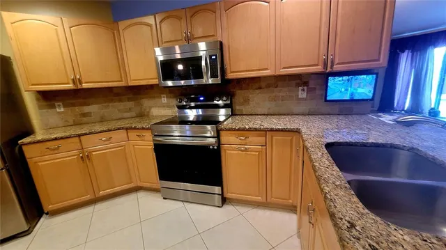 a kitchen with granite countertop cabinets stainless steel appliances and a counter space
