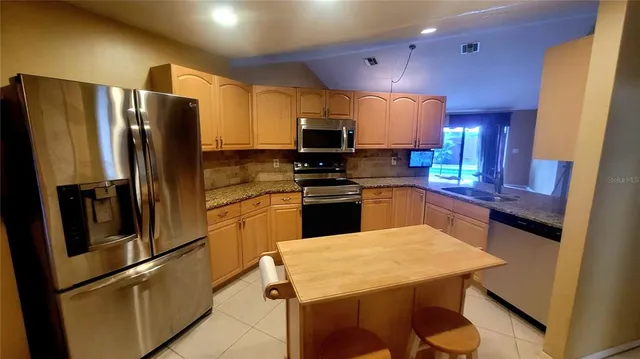 a kitchen with a sink stainless steel appliances and refrigerator