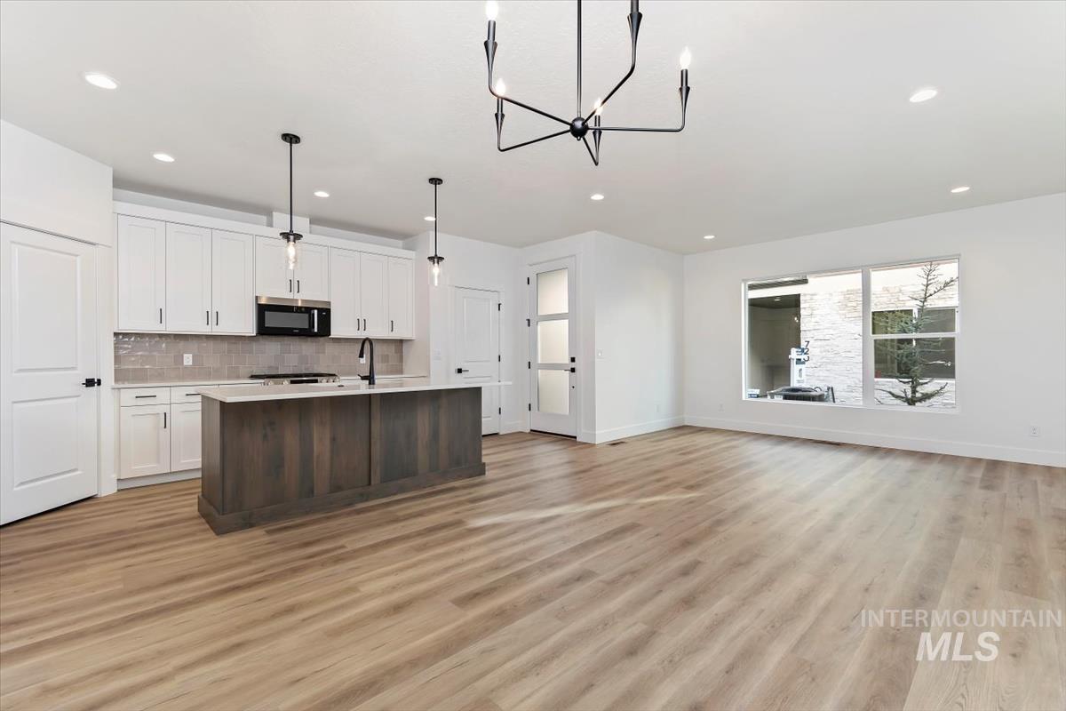 752 South Calhoun Place Star, ID 83669 - Photo 39 of 40 Kitchen featuring open floor plan, backsplash, hanging lights, stainless steel microwave, and a center island with sink