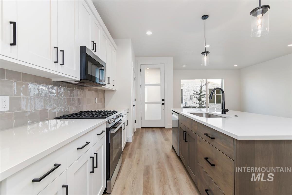 752 South Calhoun Place Star, ID 83669 - Photo 8 of 40 Kitchen with two tone cabinets, stainless steel appliances, pendant lighting, light wood-style flooring, and an island with sink