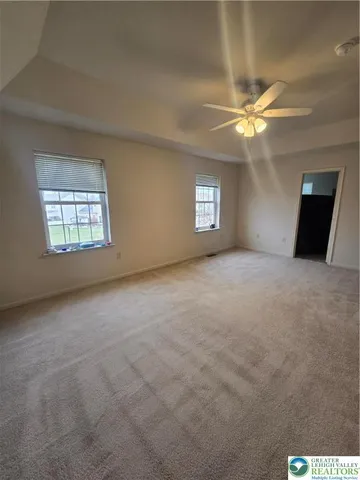 an empty room with windows and ceiling fan