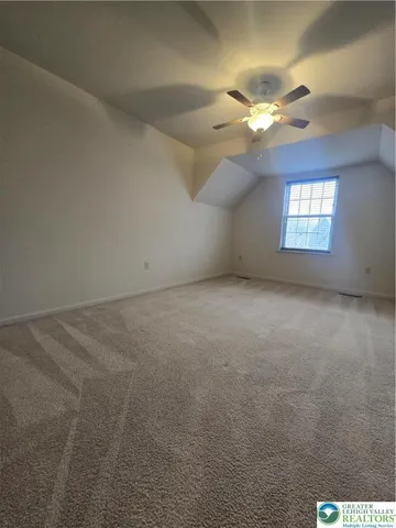 an empty room with a chandelier fan and windows