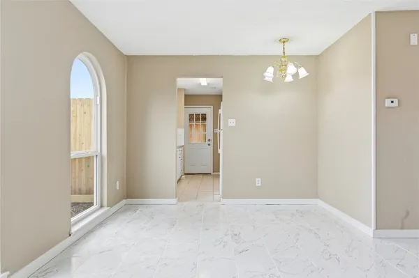 an empty room with chandelier fan and windows