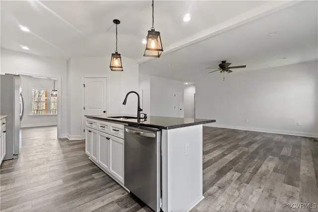 a kitchen with kitchen island granite countertop a sink cabinets and wooden floor