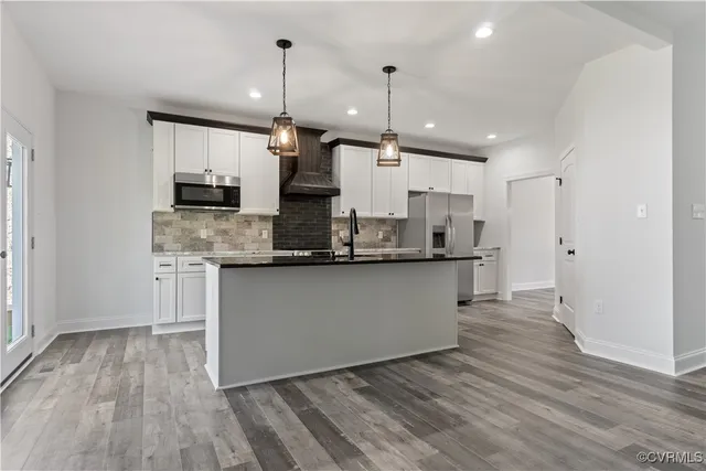 a kitchen with kitchen island granite countertop wooden floors and refrigerator